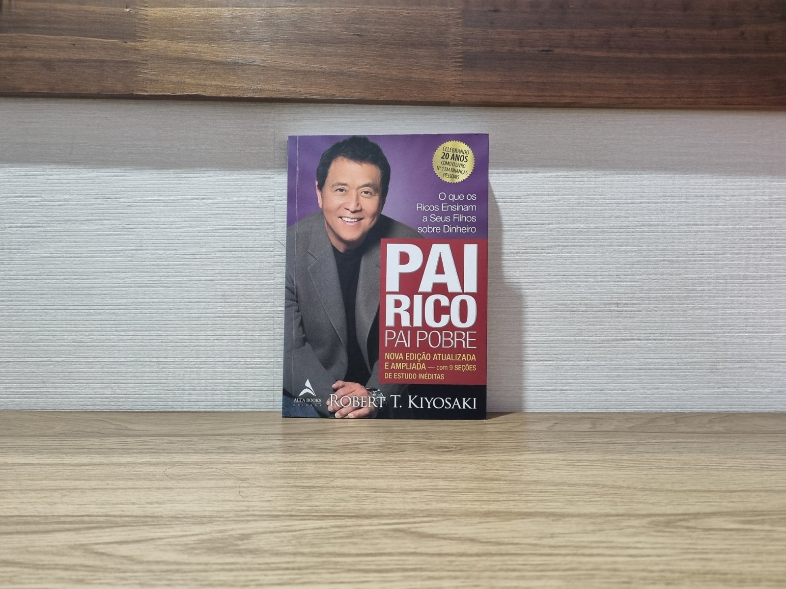 Foto real da capa do livro Pai Rico, Pai Pobre de Robert Kiyosaki, apoiado sobre uma mesa.