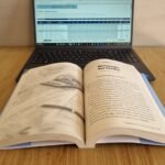 Planilha de orçamento doméstico A Quinta Parte aberta em um notebook, com o livro aberto no Capítulo 6 Eliminação das Dívidas.